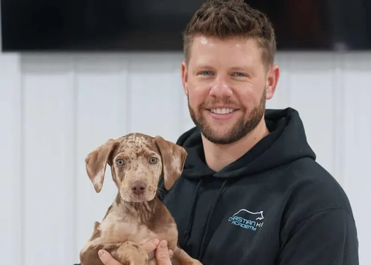 A Christian K-9 Academy trainer holding a young puppy